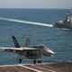 An F/A-18E Super Hornet lands on the deck of the Nimitz-class aircraft carrier USS Carl Vinson (CVN 70), with the Arleigh Burke-class missile destroyer USS Wayne E. Meyer (DDG 108) seen in the background, in the western Pacific Ocean.